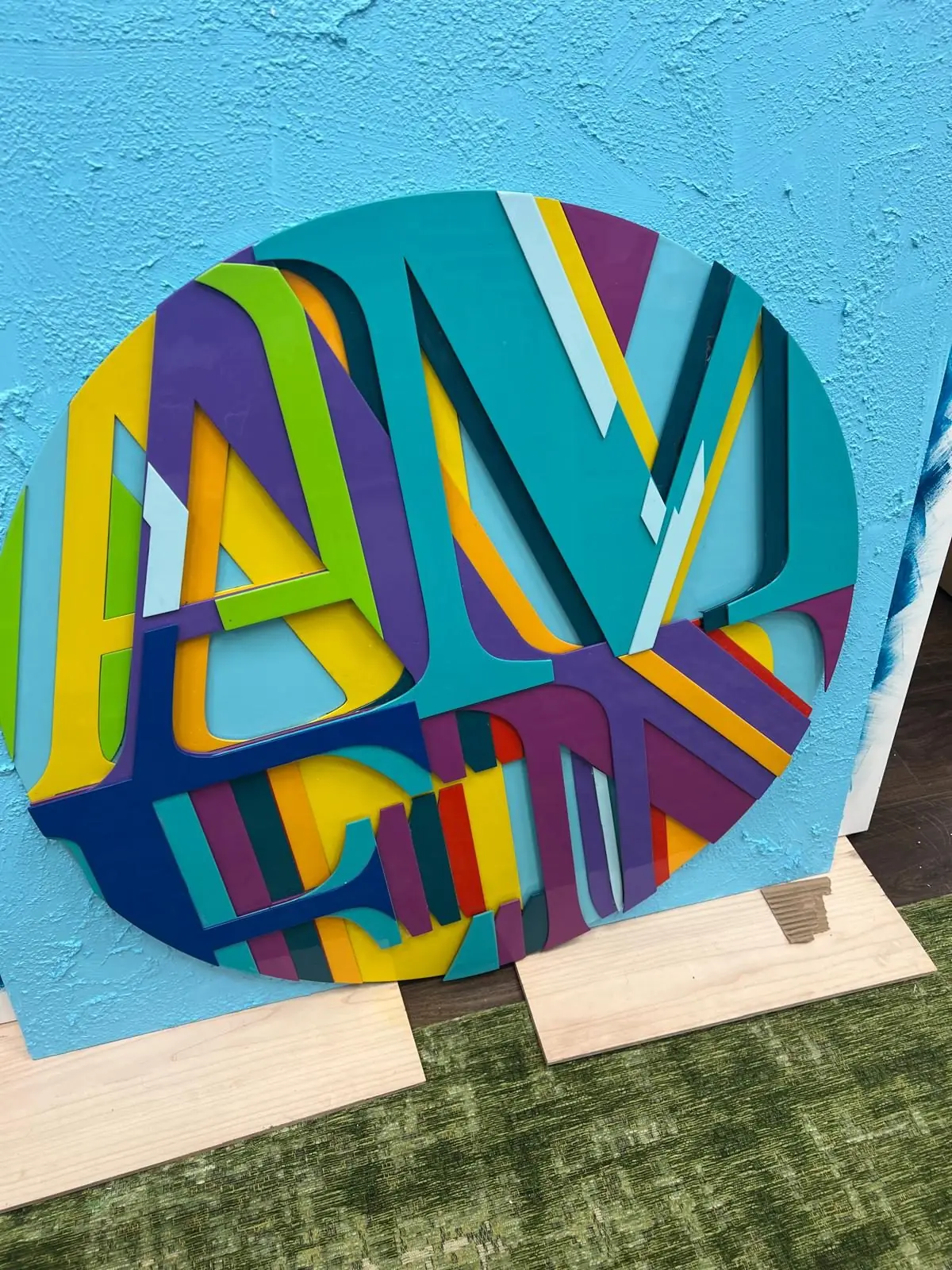 A colourful circular artwork on a blue wall, ready for display