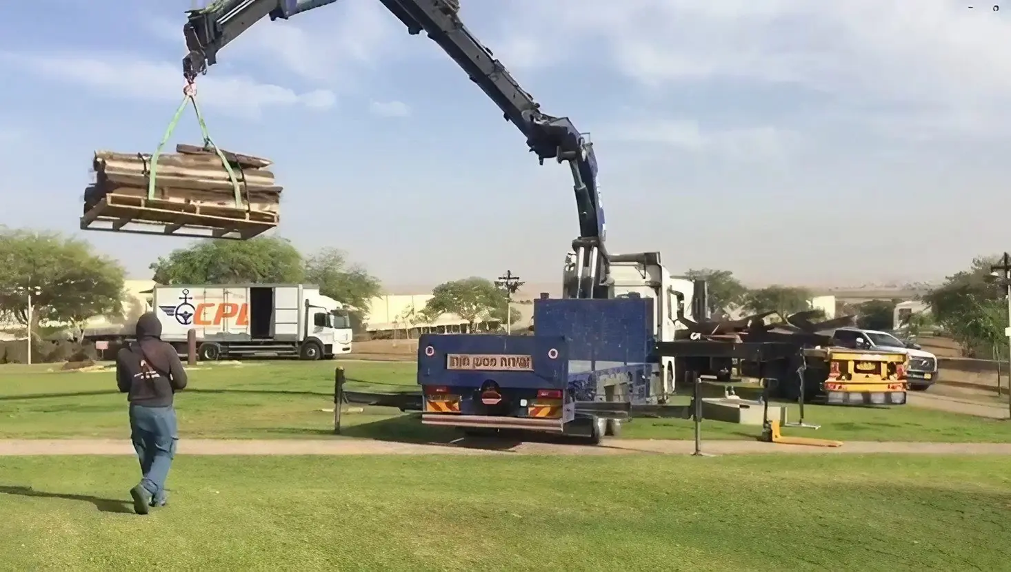 A crane truck lifting a crate in a park
