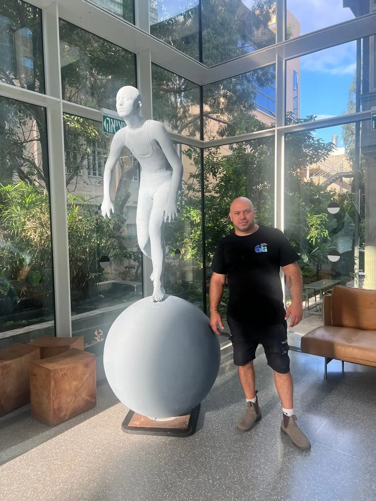 One of our team beside a white statue on a ball in a glass hall