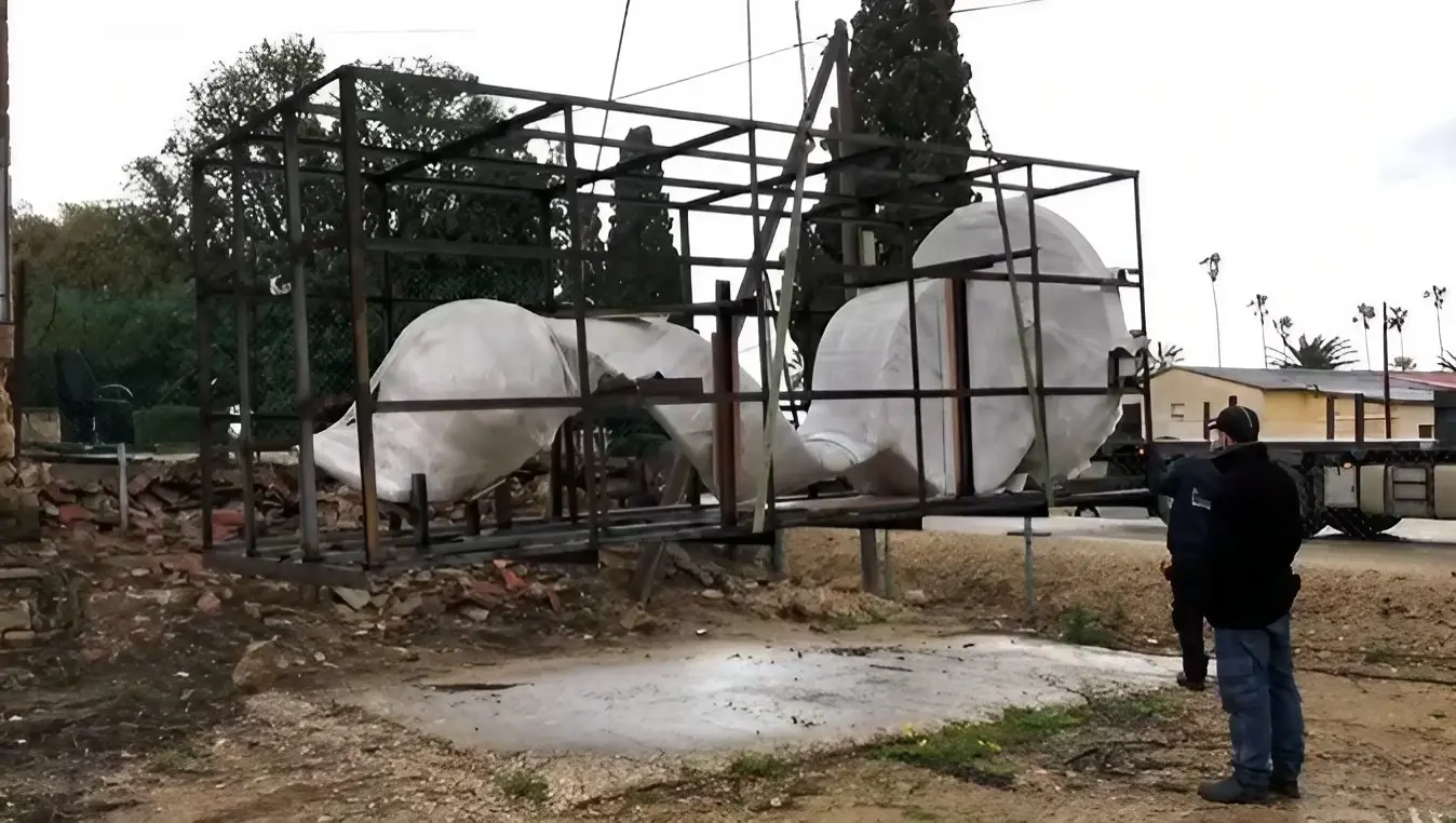 A massive statue wrapped in white on a steel frame, loaded on a truck