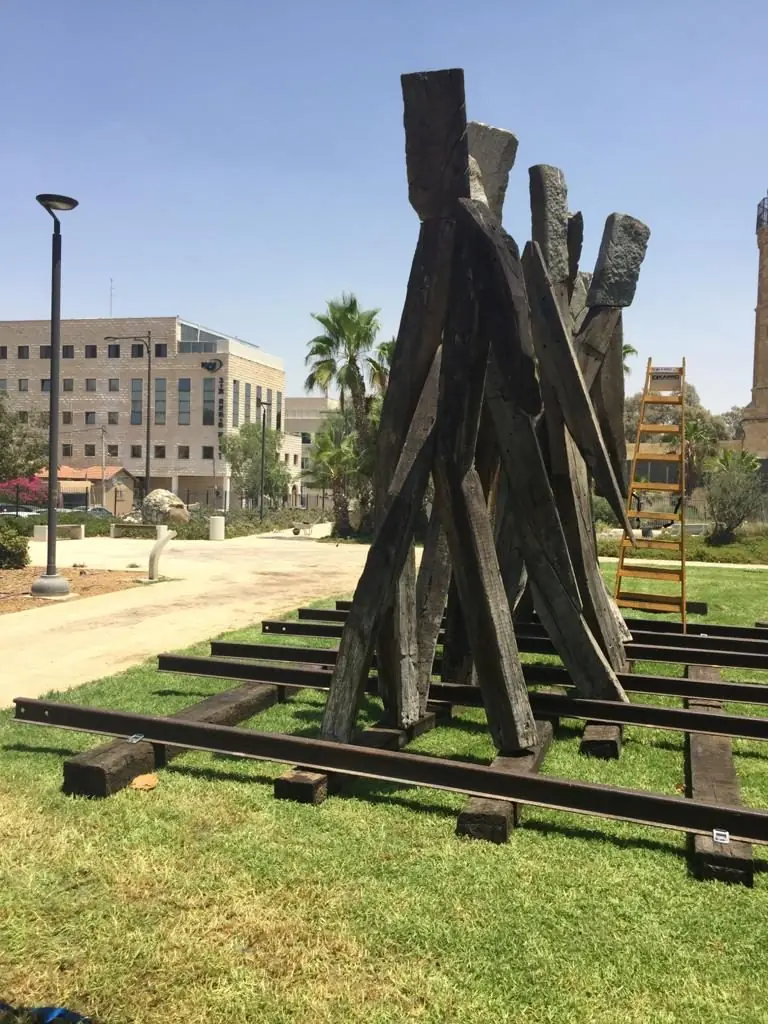 A large wooden sculpture standing on a lawn in front of the museum
